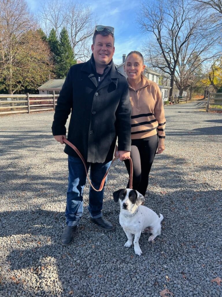 a man and woman standing next to a dog