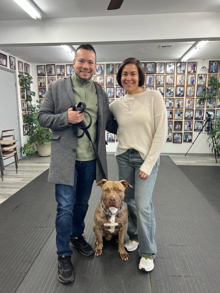 a man and woman standing next to a dog